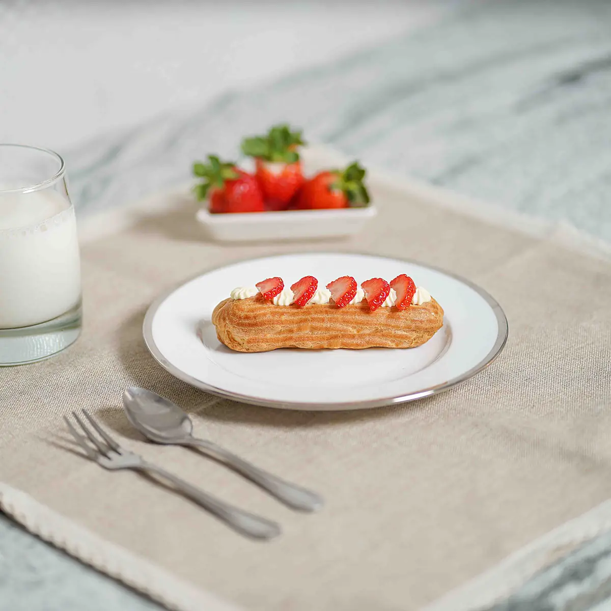 Strawberry cheesecake eclairs styled on a table