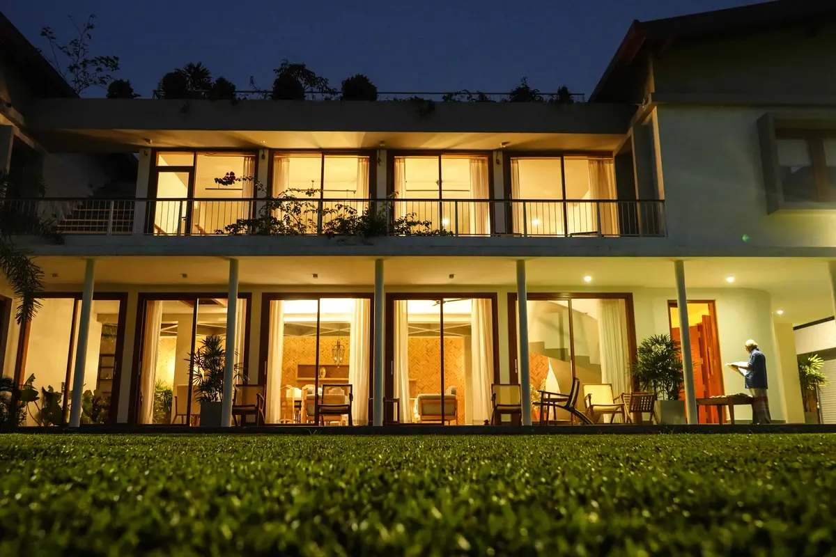 Night exterior of a modern house with warm interior lights, photographed by Flomo Notio